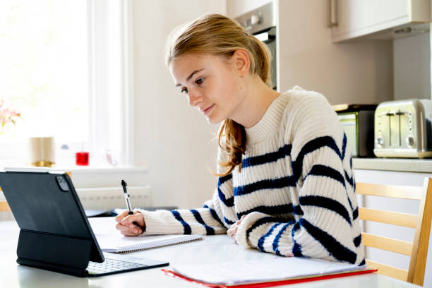Teenage girl revising at home using digital tablet Online Training - South Wales